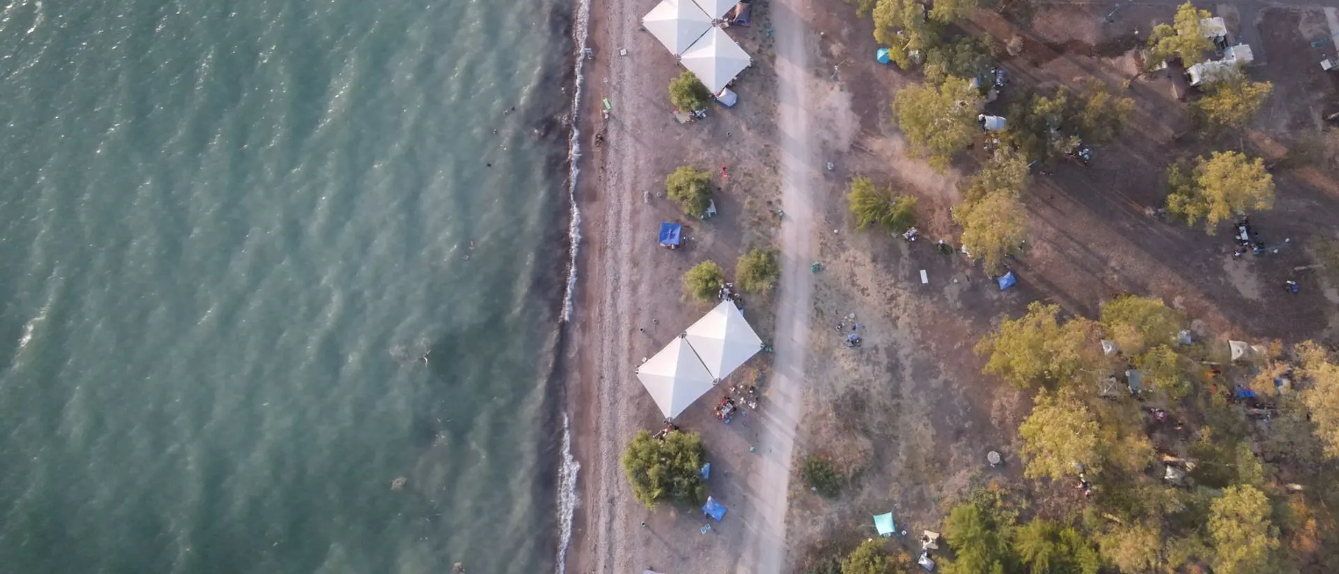A lakeside campground seen from the air, with tents along the shore